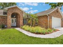 Charming brick home featuring an arched entryway, manicured lawn, and lush landscaping at 109 Hunter Point Ct, Debary, FL 32713