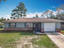 Charming single-story home with brick accents, lush lawn, and an attached one car garage in a tranquil setting at 1276 Comerwood Dr, Deltona, FL 32738