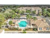 Beautiful aerial view of community pool with palm trees, clubhouse and condo building in a lush setting at 13512 Turtle Marsh Loop # 729, Orlando, FL 32837