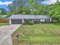 Charming single-story home featuring a metal roof, well-manicured lawn, and a welcoming gray front door at 2105 Ne 50Th Pl, Ocala, FL 34479