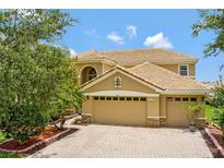 Beautiful two-story home featuring a neutral color scheme, tile roof, manicured landscaping, and a brick paver driveway at 2631 Captains Ct, Kissimmee, FL 34746