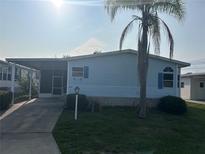 Charming home features a well-maintained lawn, a palm tree, and light blue siding with blue shutters at 622 Dreama Dr, Davenport, FL 33897