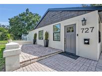 Charming home featuring a brick paver patio and stylish gray front door with decorative glass panel and sconce at 727 Seminole Ave, Orlando, FL 32804