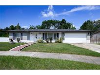 Charming single-story home with a well-manicured lawn and a welcoming brick pathway at 874 Brevard Ct, Orlando, FL 32822