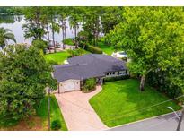Aerial view of home with brick driveway, two-car garage and luscious landscaping on a lake at 1018 Turner Rd, Winter Park, FL 32789
