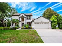 Beautiful two-story home with a manicured lawn, arched entry, and two-car garage, all under a bright blue sky at 10241 Pointview Ct, Orlando, FL 32836