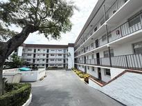 Well-maintained condo building featuring multiple levels and private balconies, surrounded by lush landscaping and mature trees at 118 S Halifax Ave # 409, Daytona Beach, FL 32118