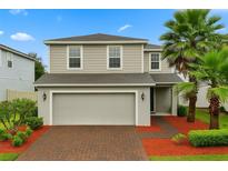 Charming two-story home with a brick driveway, two-car garage, and lush landscaping including palm trees at 17416 Painted Leaf Way, Clermont, FL 34714