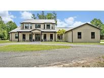 A gorgeous two-story home with a metal roof, dark trim, and lovely landscaping at 2459 Mcgregor Oaks Ln, Deland, FL 32720