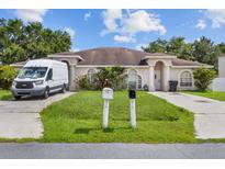 Charming single-story home with arched windows, a green lawn and mature landscaping at 621 Bluebill Ln, Poinciana, FL 34759
