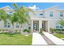 Inviting townhome featuring a covered entryway, lush landscaping, and a well-manicured lawn at 9061 Dogleg Dr, Davenport, FL 33896