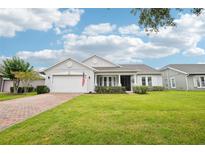Charming single-story home with a well-manicured lawn, inviting entrance, and brick paved driveway at 106 Mist Flower Ln, Groveland, FL 34736