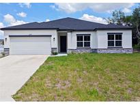 Charming single-story home with a white exterior, dark roof, and an attached two-car garage at 2699 Sw 161St Loop, Ocala, FL 34473