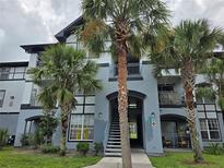 Attractive building exterior with palm trees, blue and white color scheme, balconies, and nicely landscaped grounds at 3724 Castle Pines Ln # 4234, Orlando, FL 32839