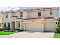 Two-story home with a red tile roof, cream-colored stucco, and a three-car garage at 6112 Broad Oak Dr, Davenport, FL 33837