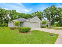 Charming single-story home with well-manicured lawn and two-car garage nestled among mature trees at 907 Pearly Ridge Ln, Lakeland, FL 33809