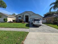 Charming single-story home featuring manicured lawn and a driveway leading to an attached garage at 12938 Maribou Cir, Orlando, FL 32828