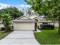 Well-maintained single-story home with a two-car garage, landscaping, and a lush green lawn at 142 Stonegate Pass, Davenport, FL 33897