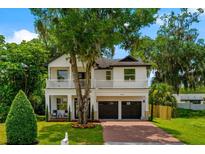 Charming two-story home features a manicured lawn, brick driveway, and inviting front porch with second-story balcony at 2607 Lafayette Ave, Winter Park, FL 32789