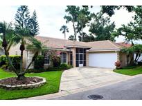 Charming single-story home with a tile roof, well-manicured lawn, and lush landscaping, including mature trees and flowering bushes at 625 Nighthawk Cir, Winter Springs, FL 32708