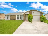 Charming single-story home with stone accents, well-maintained lawn, and a two-car garage at 7609 Winter Shade Dr, Orlando, FL 32822