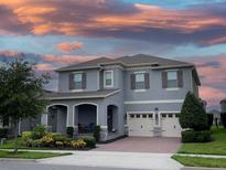 Charming two-story home showcasing a well-manicured lawn, complemented by a three-car garage and colorful sunset at 9422 Jaywood Rd, Winter Garden, FL 34787