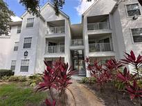 White condo building featuring balconies, stairs, and vibrant red foliage at 11568 Westwood Blvd # 1015, Orlando, FL 32821