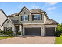 Charming two-story home with a three-car garage, tile roof, stone accents, and well-manicured landscaping at 2340 Standing Rock Cir, Oakland, FL 34787