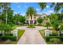 Beautiful estate featuring a circular driveway, lush landscaping, and a grand facade with classic architectural details at 2357 Alaqua Dr, Longwood, FL 32779