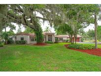 Sprawling front yard with a majestic tree draped with Spanish moss over a single-story home with a red tile roof at 4420 Conway Gardens Rd, Orlando, FL 32806