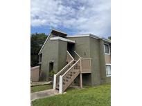 View of the building featuring an entrance staircase on the upper level and green painted exterior at 5784 Peregrine Ave # A08, Orlando, FL 32819