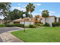 Condo exterior with tan and white stucco, lush landscaping, and tall palm trees at 1051 S Highland St # 5E, Mount Dora, FL 32757