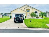 Charming, yellow home with a lush green lawn, well-manicured landscaping and a car parked in the driveway at 318 Langham Dr, Davenport, FL 33897
