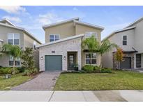 Charming two-story home with a stone accent wall, a green garage door, and a well-manicured lawn at 9227 Sommerset Hills Dr, Davenport, FL 33896