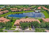 Stunning aerial view of community featuring a serene lake, pool, lush greenery, and well-maintained townhome exteriors at 10308 Belfry Cir, Orlando, FL 32832