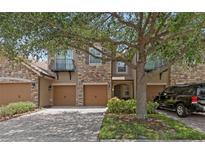 Attractive townhome exterior featuring stone accents, a private balcony, multi-car garage, and lovely tree at 10308 Belfry Cir, Orlando, FL 32832