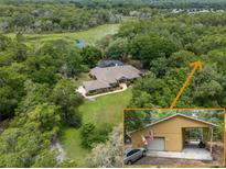 Expansive aerial view of the property showing the home, the additional garage, and a pond surrounded by lush greenery at 1550 Kevin Ln, Deland, FL 32724
