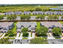 Beautiful aerial view of townhomes with manicured lawns, mature trees, and a scenic view of a lake at 1784 Fritwell Ct, Ocoee, FL 34761