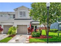 Charming two-story townhome featuring a well-manicured lawn, a one-car garage, and colorful landscaping at 1784 Fritwell Ct, Ocoee, FL 34761