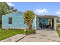 Charming home featuring light blue siding, carport, and lush green lawn at 222 Ellsworth Dr, Kissimmee, FL 34758
