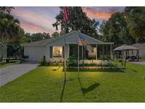 Charming single-story home with a well-manicured lawn, screened in porch, and American flags displayed at 2597 Cr 426F, Lake Panasoffkee, FL 33538
