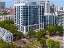 A modern high-rise condo building with multiple floors of balconies and large windows surrounded by greenery at 260 S Osceola Ave # 1406, Orlando, FL 32801