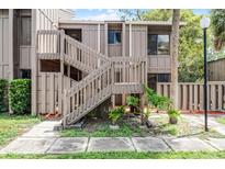 Two-story condo with light brown wooden siding and exterior stairways to the upper unit entrances at 5301 Burning Tree Dr # F, Orlando, FL 32811