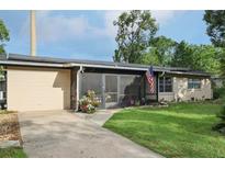 Single-story home featuring a screened porch, solar panels, landscaping, and an American flag displayed outside at 618 Acapulca Way, Altamonte Springs, FL 32714