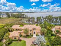Stunning lakefront home with lush landscaping, tile roof, and brick driveway at 11103 Bridge House Rd, Windermere, FL 34786