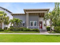 Charming two-story home with gray siding, covered porch, landscaped yard, and a red front door at 13334 Beebe Aly, Orlando, FL 32827