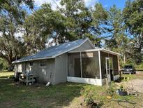 Quaint single-story home featuring a screened porch, neutral paint, and set amidst mature trees at 2847 Cr 756, Webster, FL 33597