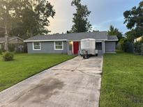 Charming single story home boasts a gray exterior, well manicured lawn and a bright red front door at 2847 W Harwood St # 0, Orlando, FL 32805