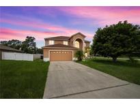 Inviting two-story home featuring an arched entryway, attached two-car garage, and a lush front lawn at dusk at 442 Churchill Ct, Kissimmee, FL 34759