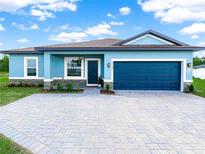 Charming single-story blue home featuring a two-car garage and a well-manicured front yard at 527 Rio Grande Dr, Poinciana, FL 34759